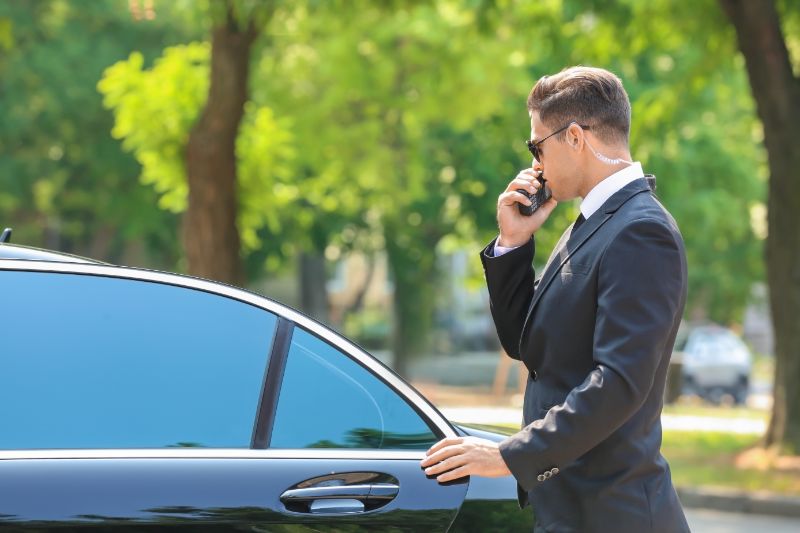 Bodyguard opening cars door talking on radio device
